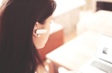 woman-wearing-earpiece-using-white-laptop-computer-210647