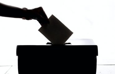 person-dropping-paper-on-box-1550337